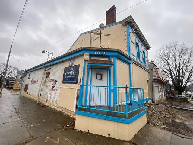 Ventura Builders Group office on a wet street corner: tan facade with blue trim and large company sign.