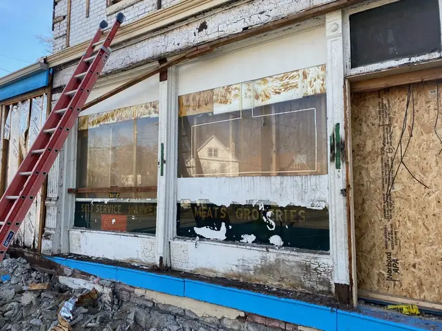 Weathered storefront with peeling paint; gold lettering reads Self Service Market and Meats Groceries; ladder and rubble out front.